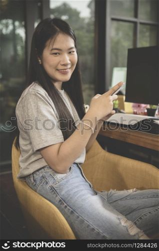 asian younger freelance with smart phone in hand working at home office