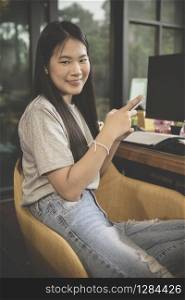 asian younger freelance with smart phone in hand working at home office