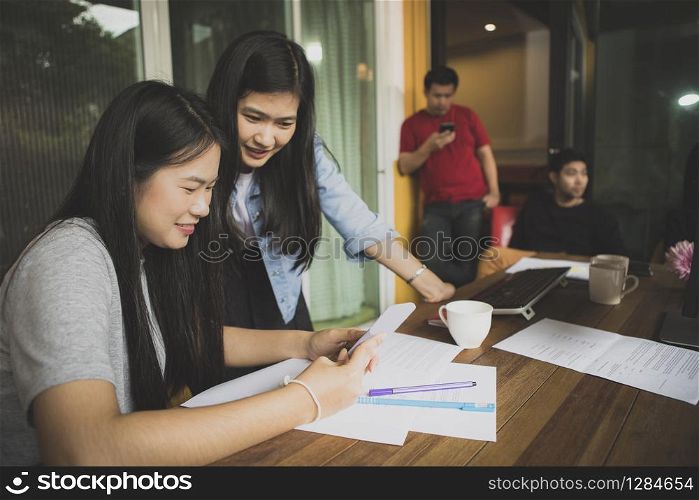 asian younger freelance woman talking to working friend in modern office