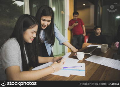 asian younger freelance woman talking to working friend in modern office