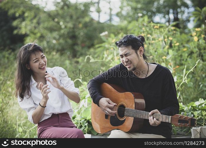 asian younger man and woman playing guitar with happiness emotion