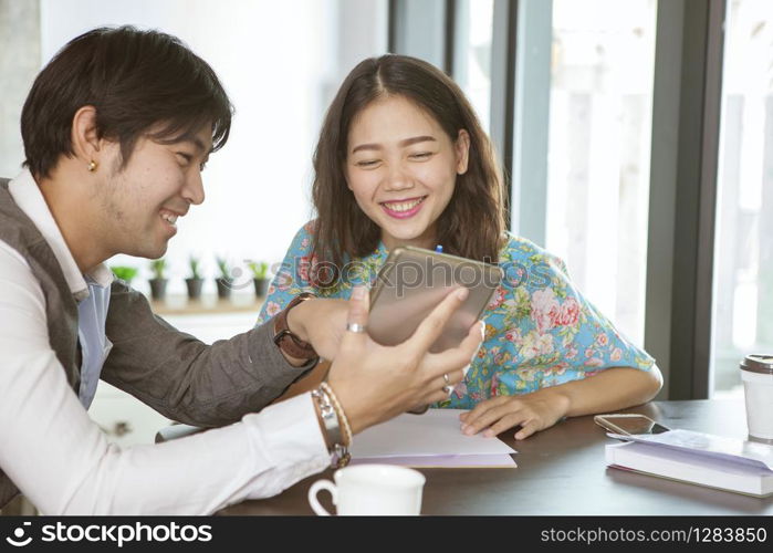 asian younger man and woman relaxing with computer tablet in hand in coffee shop ,social media and digital connecting technology lifestyle