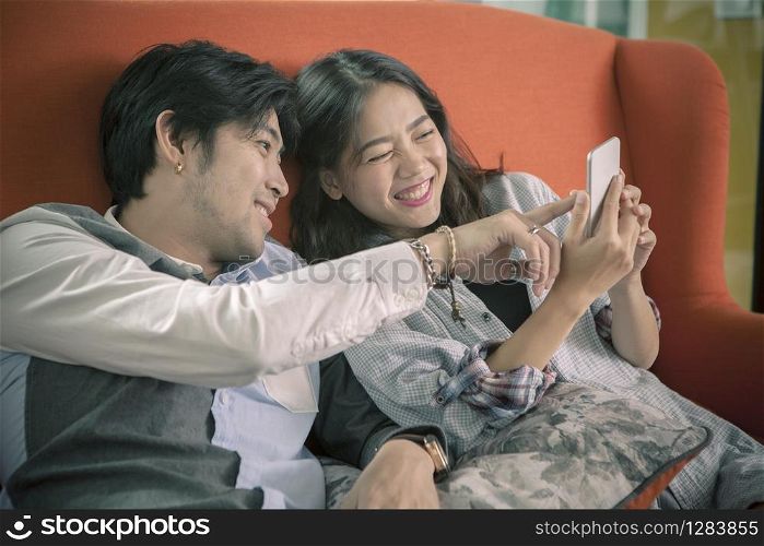 asian younger man and woman watching on smart phone with happy face,internet and social media connecting concept
