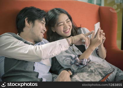 asian younger man and woman watching on smart phone with happy face,internet and social media connecting concept