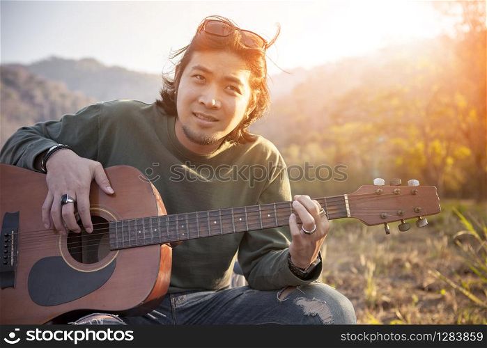 asian younger man relaxing outdoor with old guitar ,for people leisure vacation and traveling