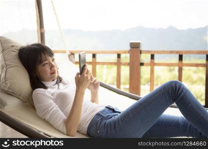 asian younger woman toothy smiling with happiness holding smart phone in hand ,relaxing lifestyle