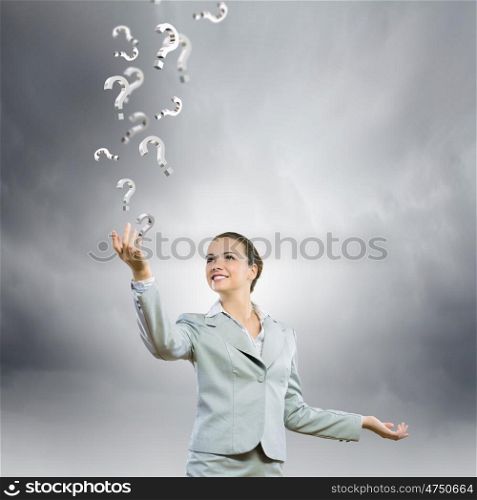 Asking questions. Image of young attractive businesswoman holding question marks in hand