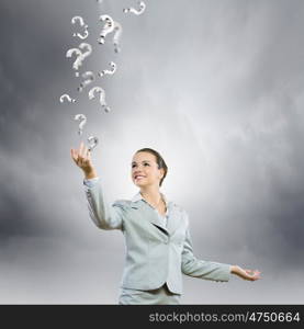 Asking questions. Image of young attractive businesswoman holding question marks in hand