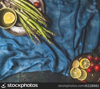 Asparagus and cooking ingredients on dark blue background, top view, place for text