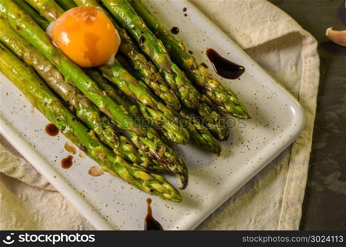 Asparagus cooked with egg served on a white ceramic tray on the table.