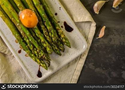 Asparagus cooked with egg served on a white ceramic tray on the table.