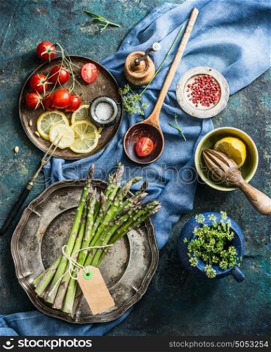 Asparagus cooking preparation with ingredients and cooking spoon on rustic kitchen table background, top view. Healthy seasonal food or vegetarian eating concept