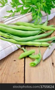 Asparagus green beans, napkin, knife, parsley on a wooden boards background