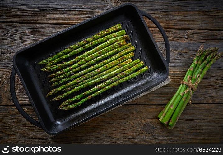 asparagus grilled on cast iron grill pan on wood table with tomatoes and pepper. asparagus grilled on cast iron grill pan on wood