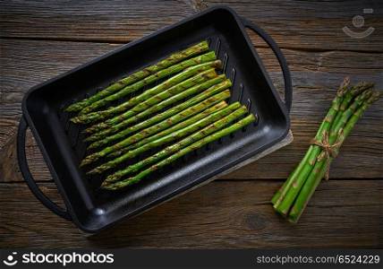 asparagus grilled on cast iron grill pan on wood table with tomatoes and pepper. asparagus grilled on cast iron grill pan on wood