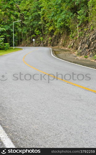 Asphalt curved road in tropical rain forest