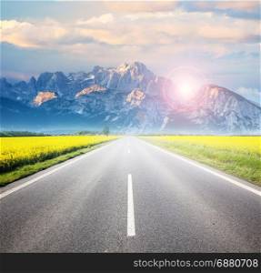 Asphalt road among the summer field and mountain on horizon. Beautiful countryside landscape