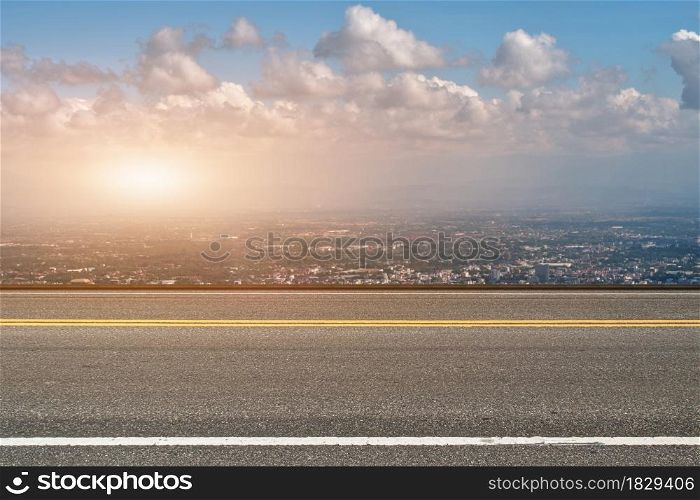Asphalt road and cityscape at sunset background.