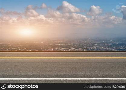 Asphalt road and cityscape at sunset background.