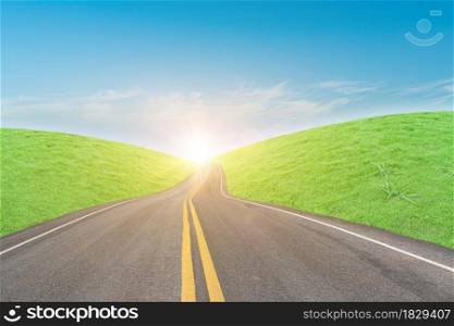 Asphalt road and green grass field in countryside on sunny day.