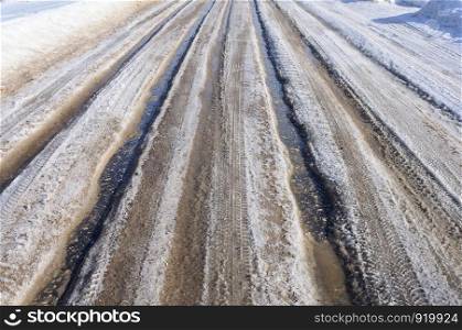 Asphalt road background with melting snow, sunny spring day