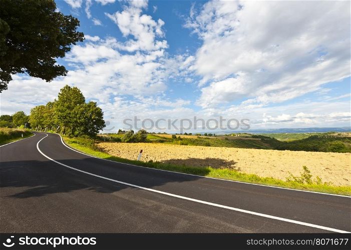 Asphalt Road between Autumn Plowed Fields in the Tuscany