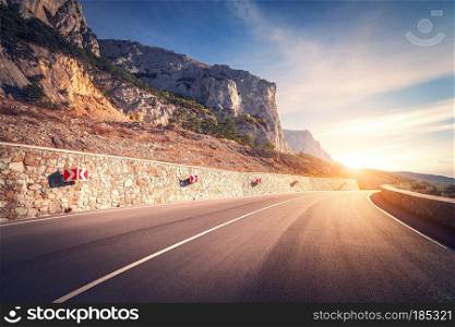 Asphalt road. Colorful landscape with beautiful mountain road with a perfect asphalt and road signs. Sunrise in summer. Vintage toning. Travel background. Highway at mountains. Speed. Retro style