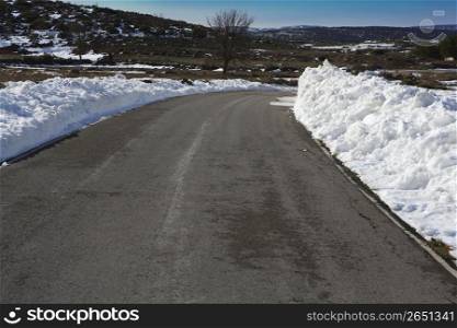 asphalt road curve with snow in both side borders