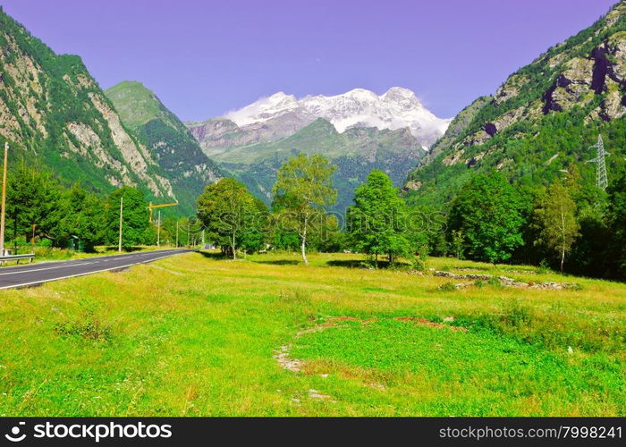 Asphalt Road Leading to the Snowy Peaks of the Alps