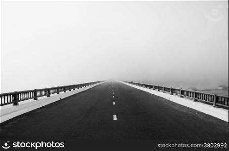 Asphalt road on big bridge cross the lake in fog at morning, the way like arrow, direction to white future, atmosphere full misty