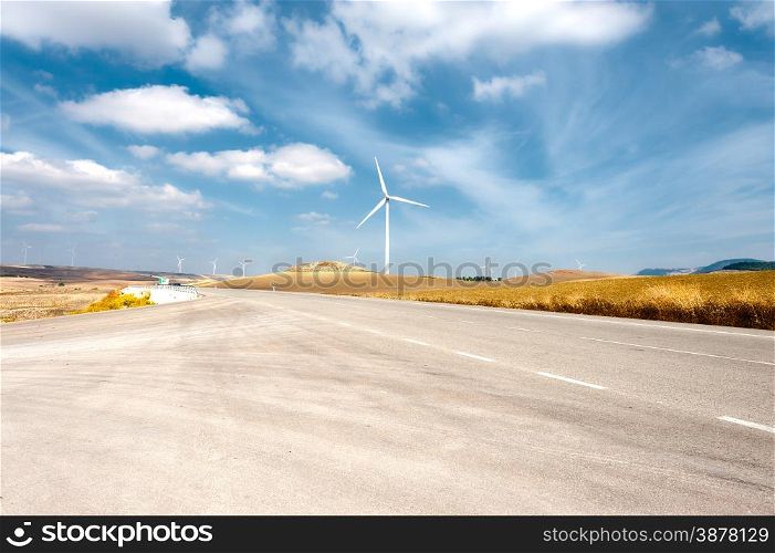 Asphalt Road on the Background of the Modern Wind Turbines Producing Energy in Spain