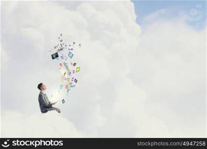 Aspiration for education. Young businessman sitting on cloud with book and icons flying in air