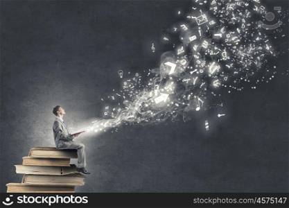 Aspiration for education. Young businessman sitting on pile of old books and characters flying in air