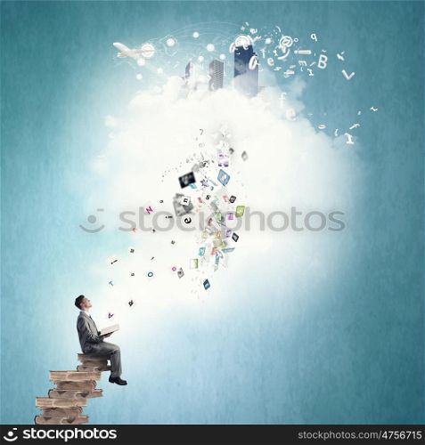Aspiration for education. Young businessman sitting on pile of old books and icons flying in air