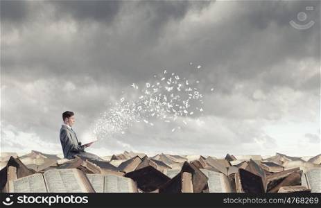 Aspiration for education. Young businessman sitting on pile of old books and characters flying in air