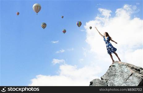 Aspiration to freedom. Young elegant woman trying to reach sky