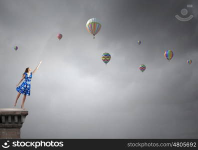 Aspiration to freedom. Young elegant woman trying to reach sky