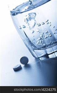 aspirin pills and glass of water toned blue