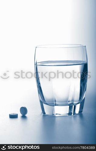 aspirin pills and glass of water toned blue