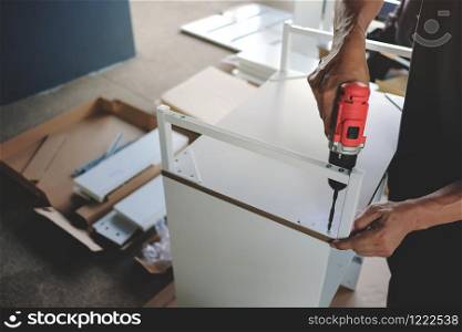 Assembling Furniture at Home. Moving for a New House or DIY Concept. Craftsman using Cordless Screwdriver to Installing the Cabinet.