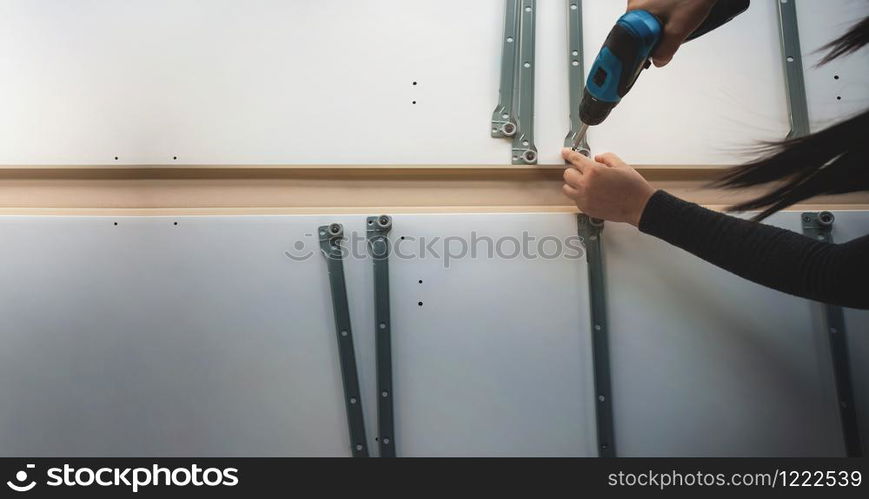 Assembling Furniture at Home. Moving for a New House or DIY Concept. Woman using Cordless Screwdriver to Installing the Cabinet. Top View