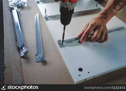 Assembling Furniture at Home. Moving for a New House or DIY Concept. Craftsman using Cordless Screwdriver to Installing the Cabinet.