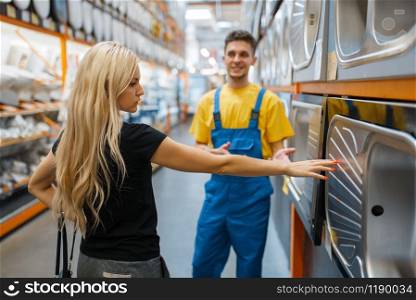 Assistant and female buyer in hardware store. Seller in uniform and woman in diy shop, shopping in building supermarket. Assistant and female buyer in hardware store