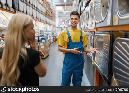 Assistant and female buyer in hardware store. Seller in uniform and woman in diy shop, shopping in building supermarket