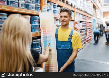 Assistant and female customer in hardware store. Seller in uniform and woman in diy shop, shopping in building supermarket