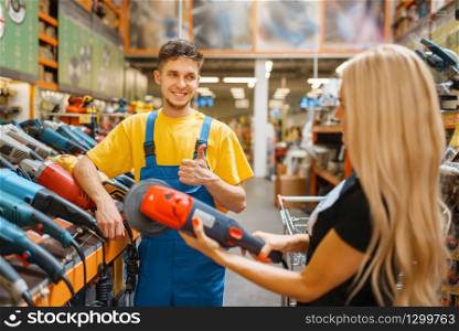 Assistant and female purchaser in hardware store. Seller in uniform and woman in diy shop, shopping in building supermarket