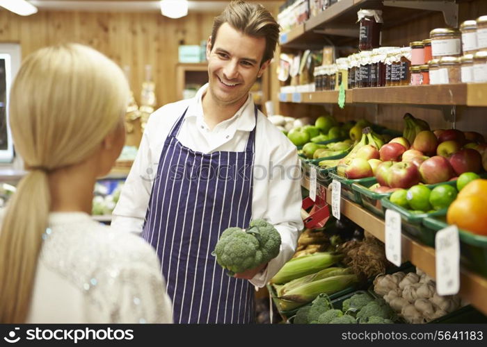 Assistant Helping Customer At Vegetable Counter Of Farm Shop