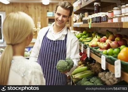 Assistant Helping Customer At Vegetable Counter Of Farm Shop