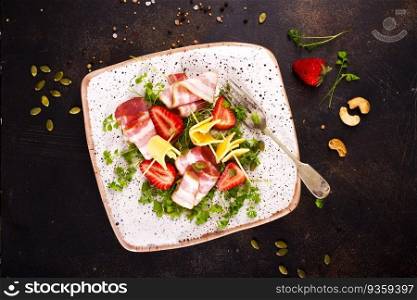 Assorted cheeses and prosciutto with strawberry on plate