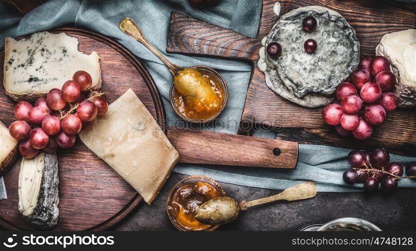 Assorted cheeses on rustic cutting boards with grape and honey mustard sauces, top view